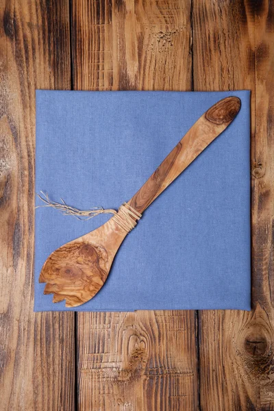 Blue kitchen towel and wooden spoon on old wooden burned table o — Stock Photo, Image
