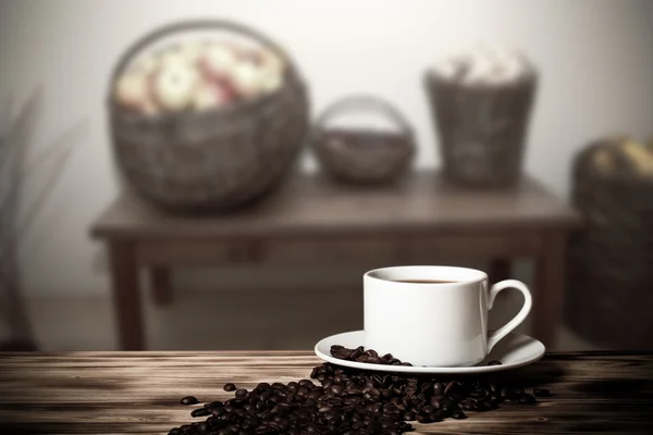 Kawa w filiżance na drewniany stół naprzeciwko niewyraźne zakwaterowanie w s — Zdjęcie stockowe