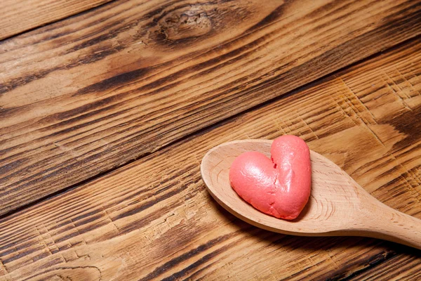 Cuchara de madera y corazones rojos en una vieja mesa o tablero quemado de madera — Foto de Stock