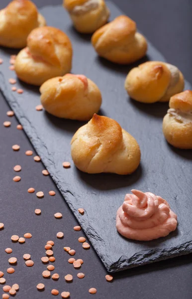 Jogo de pequenos profiteroles em uma chapa de ardósia preta. Profundidade superficial — Fotografia de Stock