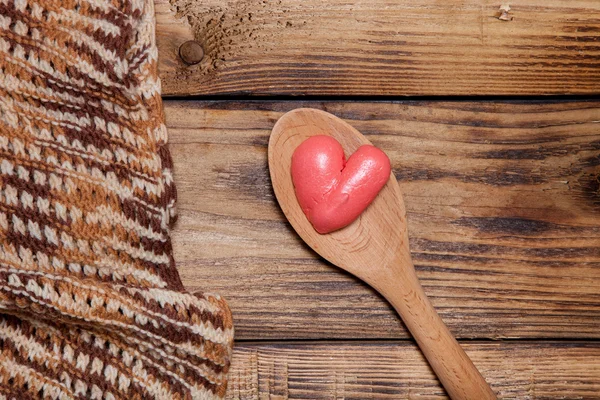 Bufanda de punto, cuchara de madera y corazones rojos en madera vieja quemada — Foto de Stock
