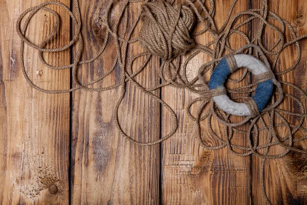 Rope and lifebuoy on old wooden burned table or board for backgr — Stock Photo, Image