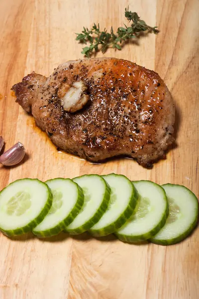 Fresh fried meat with thyme, garlic and cucumber on light wooden — Stock Photo, Image