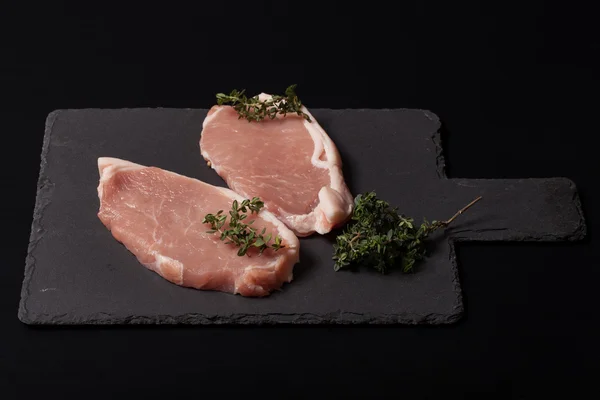 Bistecche di carne fresca su sfondo nero ardesia — Foto Stock