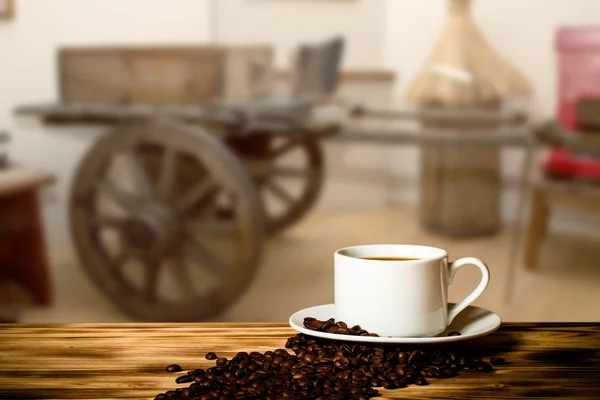 Café en una taza sobre mesa de madera frente a un desenfocado el interio —  Fotos de Stock