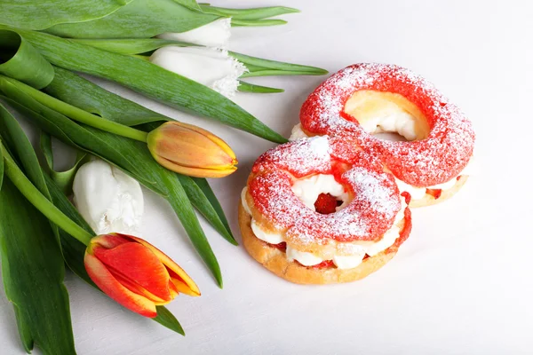 Pasteles de crema caseros con crema y manojo de tulipanes de primavera en —  Fotos de Stock