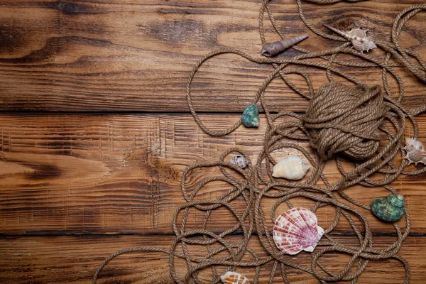 Corde et coquillages sur une vieille table ou une planche brûlée en bois pour le backg — Photo