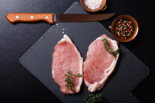 Bistecche di carne fresca su sfondo nero ardesia — Foto Stock