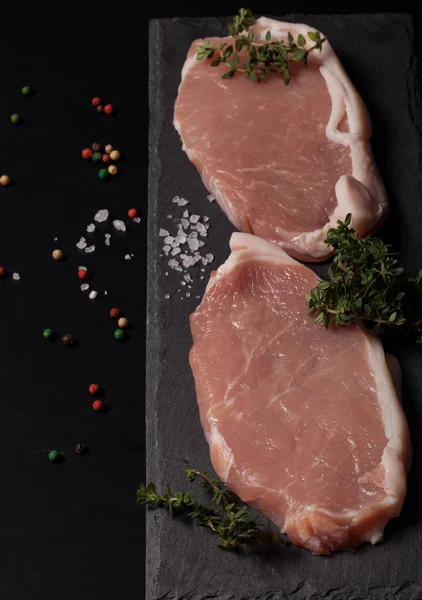 Fresh meat steaks on black slate background — Stock Photo, Image