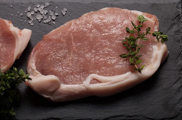 Bistecche di carne fresca su sfondo nero ardesia — Foto Stock