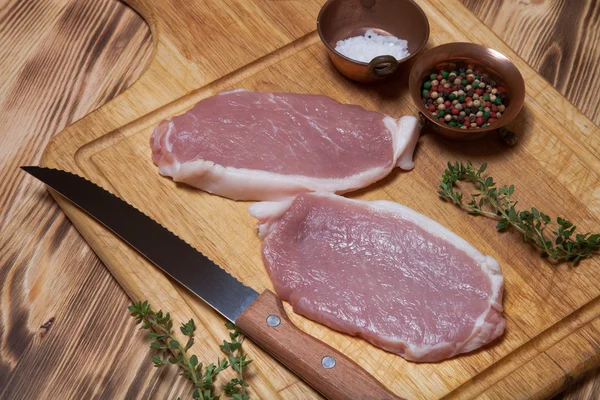 Fresh meat steaks on light wooden cutting board — Stock Photo, Image