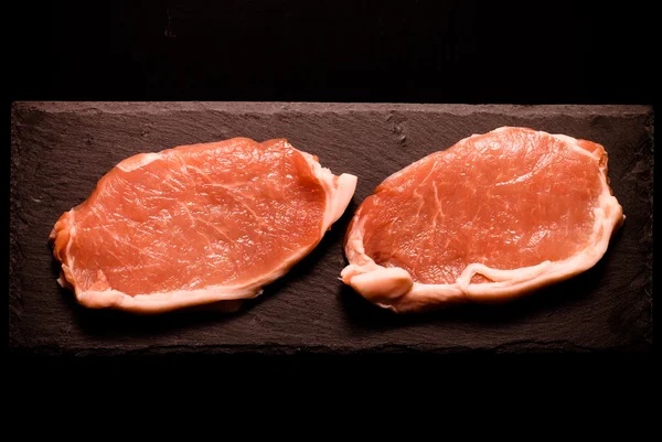Świeże mięso steki na czarnym tle łupków. Stonowanych — Zdjęcie stockowe