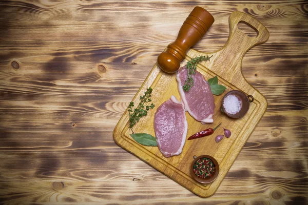 Bifes de carne fresca na placa de corte de madeira leve. Tonificado — Fotografia de Stock