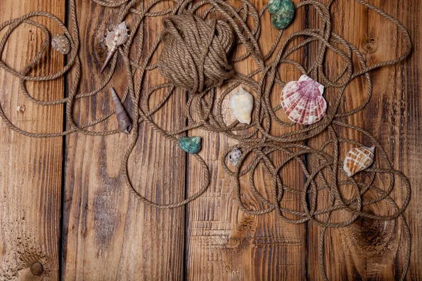 Rope and seashells on old wooden burned table or board for backg — Stock Photo, Image