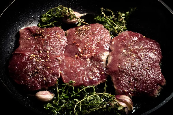 Свіже сире м'ясо з чебрецем смажать на чорній сковороді. Тонований — стокове фото