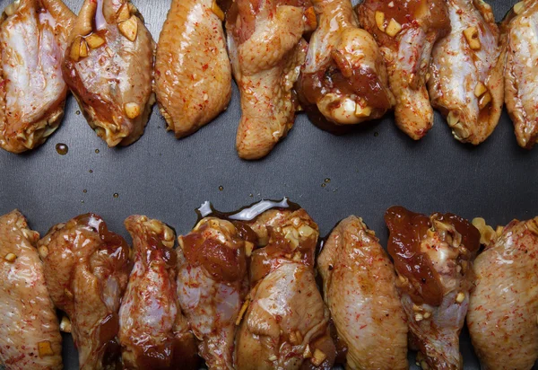 Alitas de pollo marinadas en una sartén negra —  Fotos de Stock