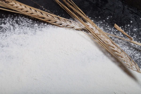 Wheat ears and sprinkle flour on black background — Stock Photo, Image