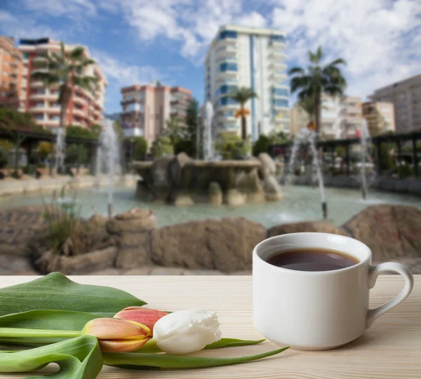 Tea cup with tulips on the wooden table opposite blurred backgro — Stock Photo, Image