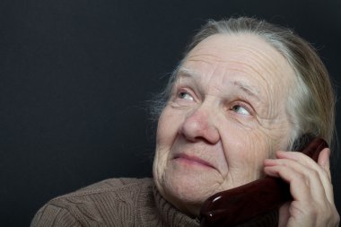 Yaşlı kadın koyu arka plan üzerinde telefon ile portresi