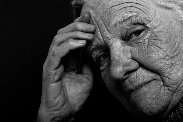 Porträt einer älteren Frau auf dunklem Hintergrund. gemildert — Stockfoto