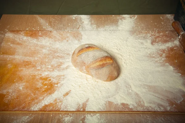 Pão caseiro fresco caiu em um monte de farinha. Tonificado — Fotografia de Stock