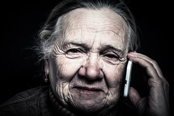 Portrait of elderly woman with telephone on dark background. Ton — Stock Photo, Image