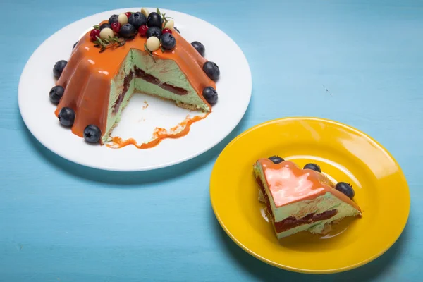 Pastel de mousse naranja con bayas en la mesa de madera azul —  Fotos de Stock