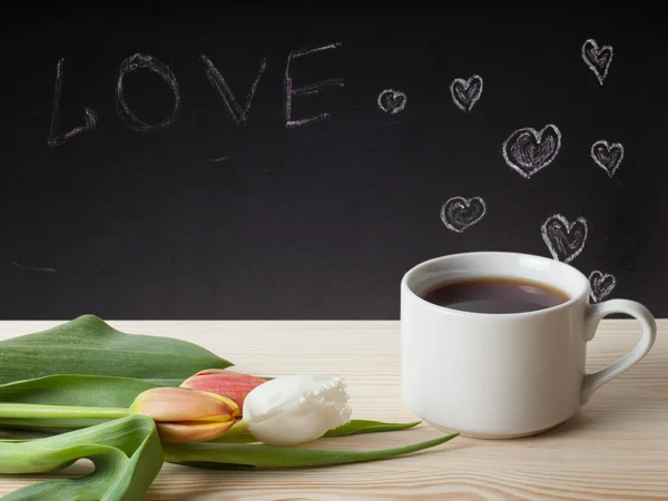 Tema romántico en una pizarra detrás de una mesa de madera con taza de — Foto de Stock