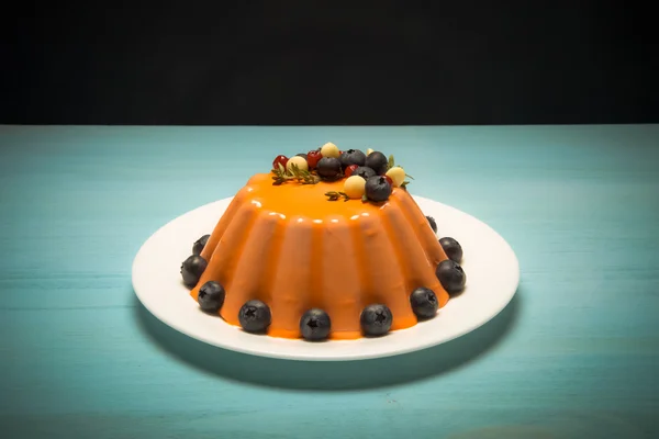 Bolo de mousse laranja com bagas na mesa de madeira azul. Tonificado — Fotografia de Stock