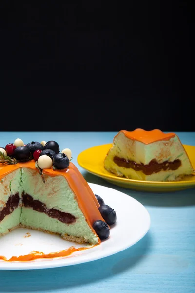 Pastel de mousse naranja con bayas en la mesa de madera azul —  Fotos de Stock