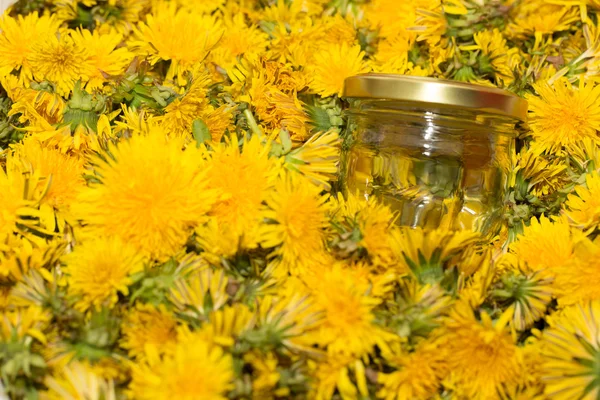 Glass jar on natural background of yellow dandelions. Shallow de — Stock Photo, Image
