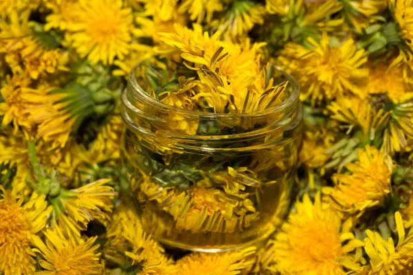 Glass jar on natural background of yellow dandelions. Shallow de — Stock Photo, Image