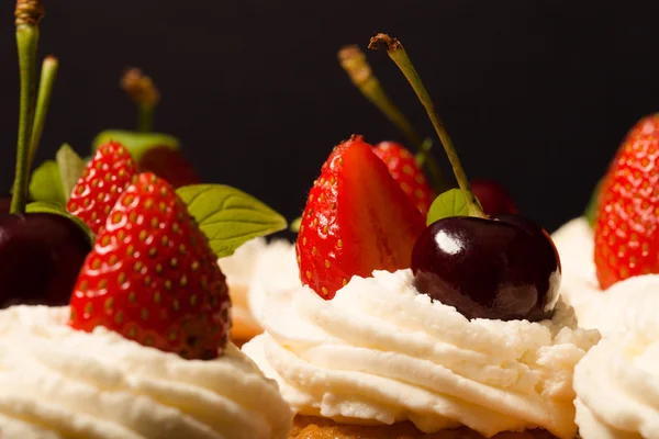 Frische Cupcakes mit Sahne und Beeren. geringe Schärfentiefe. s — Stockfoto