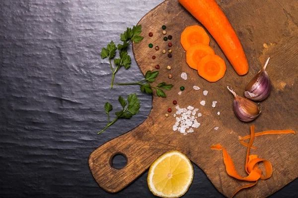 Salt, pepper and vegetables on old wood background — Stock Photo, Image