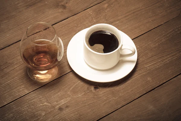 White cup of coffee and cognac in a glass on old wooden table. T — Stock Photo, Image