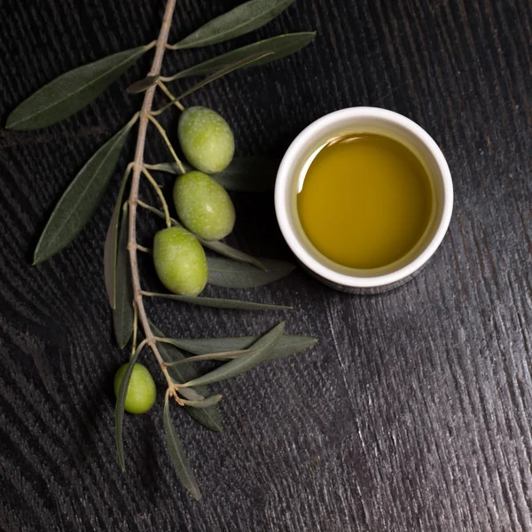 Branch of olive tree with green olive berries and cap of fresh o