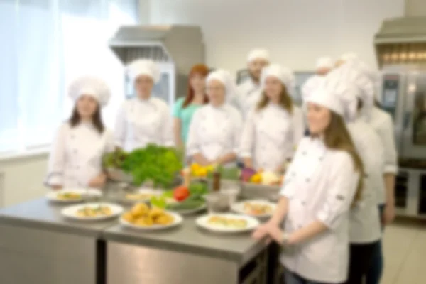 The team of cooks in the kitchen of the restaurant. Defocused