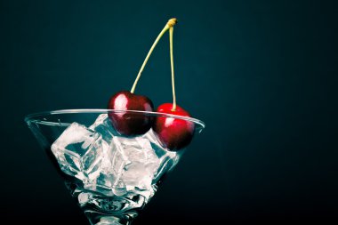 Kiraz meyveleri siyah arka plan üzerine bir martini cam. Tonda
