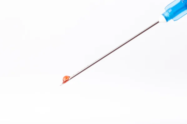 Gota de medicamento al final de la aguja de la jeringa sobre una ligh —  Fotos de Stock