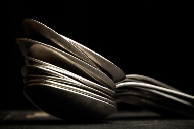 Çok fazla siyah bir zemin üzerine metal çatal bıçak takımı. Seçici odak. Sha