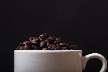 Kahve çekirdekleri fincan siyah arka plan üzerine