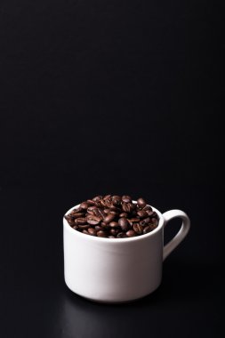 Kahve çekirdekleri fincan siyah arka plan üzerine