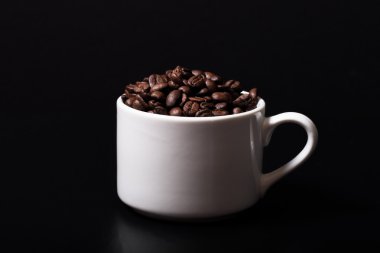 Kahve çekirdekleri fincan siyah arka plan üzerine