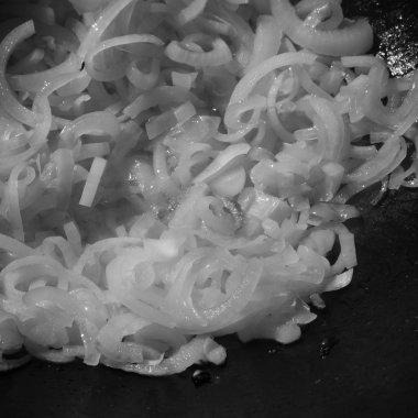 Bir tavada doğranmış soğan çok. Seçici odak. Tonda