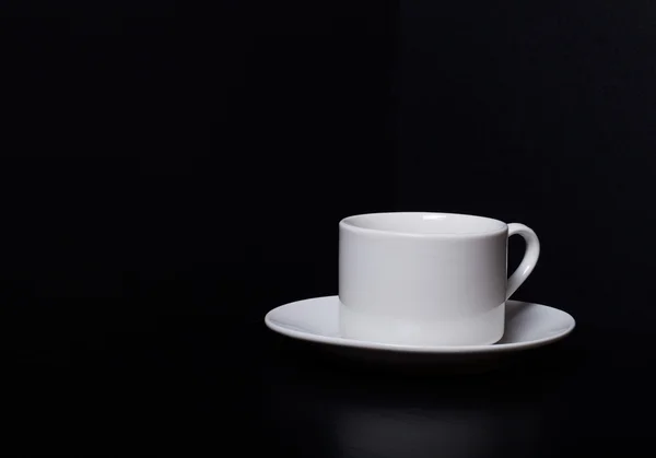 Vit kopp och fat på en svart bakgrund — Stockfoto