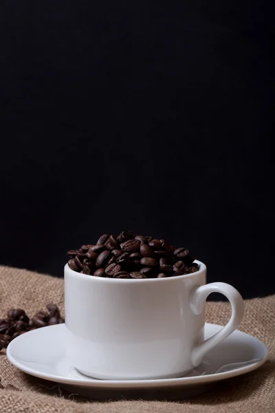 Kaffeebohnen und Kaffee in Tasse auf Büschel. Selektiver Fokus — Stockfoto