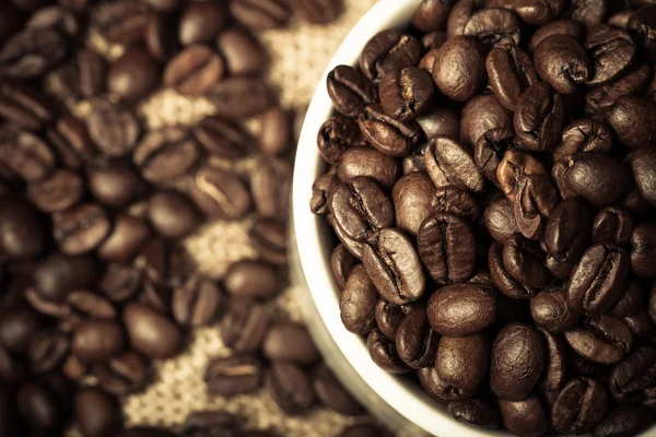 Koffiebonen en koffie in cup op jute. Selectieve aandacht. Toned — Stockfoto