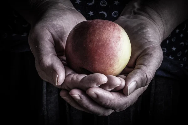 Čerstvé jablko v rukou starší žena. Tónovaný — Stock fotografie