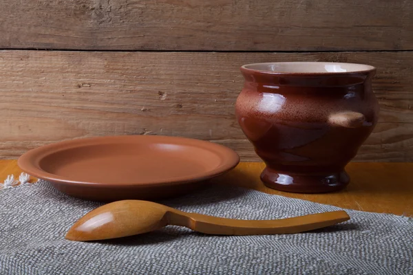 Rustic still life. Clay pot, spoon and plate on linen napkin. Wo — Stock Photo, Image