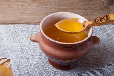 Ghee ve kaşık keten peçete ile toprak kap. Rustik natürmort.